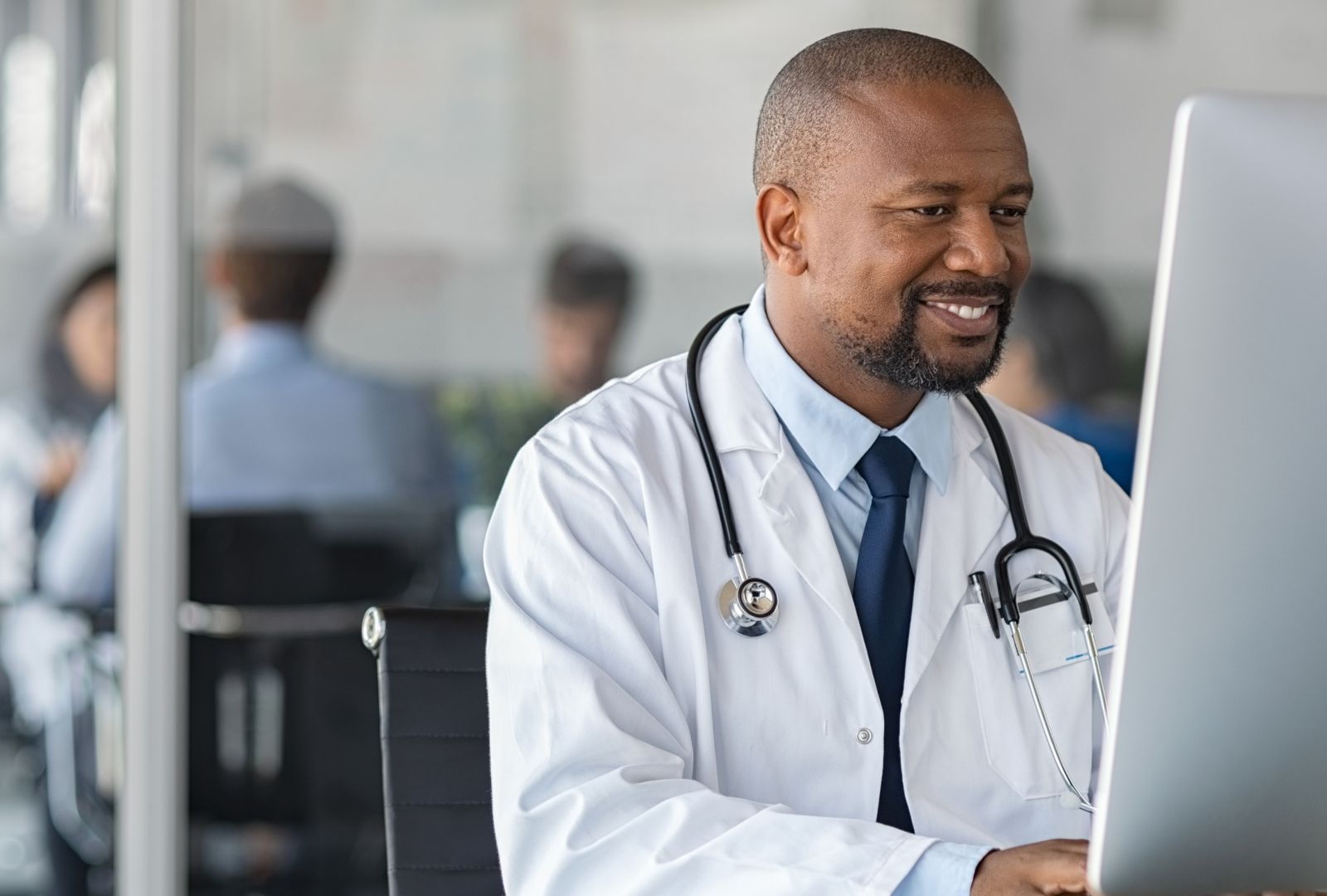 A doctor smiling as he works on a computer